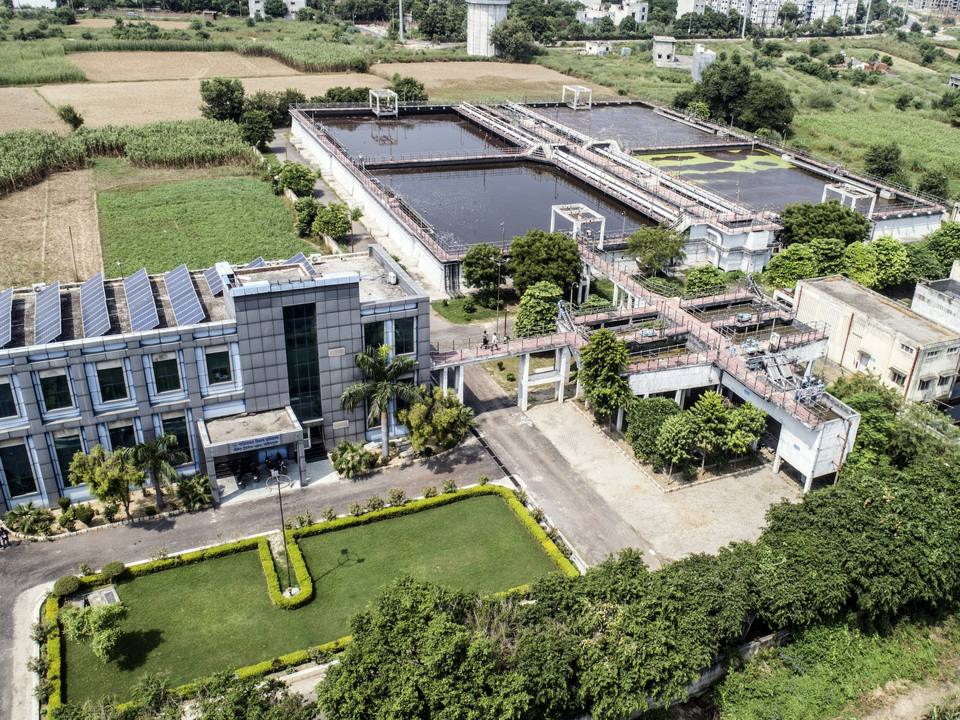 Aerial view of a water treatment plant with solar panels on the roof of its main building